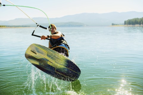 Caucasian man wakeboarding on lake