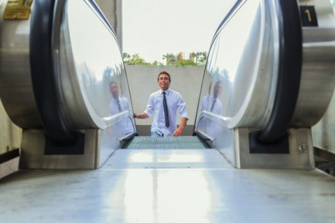 Hispanic businessman riding escalator