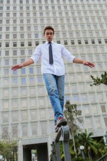 Hispanic businessman balancing on urban railing