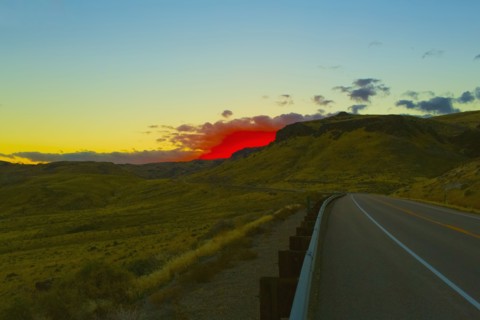 Red sunset over rural road and hillside
