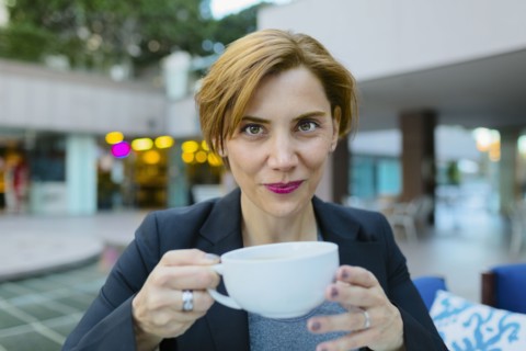 Caucasian businesswoman drinking coffee at sidewalk cafe