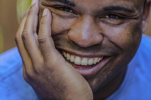 Close up of smiling Black man resting chin in hand