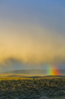 Rainbow and clouds over desert landscape