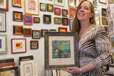 Caucasian artist holding artwork in gallery