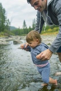 Father helping daughter walk in river