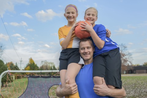 Caucasian father holding daughters in field