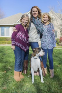 Caucasian mother and daughters smiling with dog