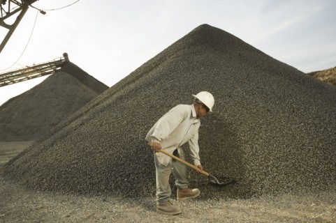 Hispanic man shoveling gravel