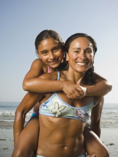 Hispanic mother giving daughter piggyback ride