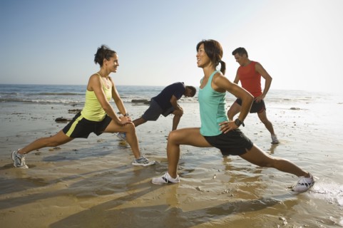 Multi-ethnic runners stretching at beach
