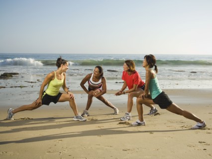 Multi-ethnic runners stretching at beach