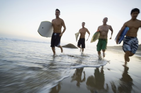 Multi-ethnic men running with surfboards