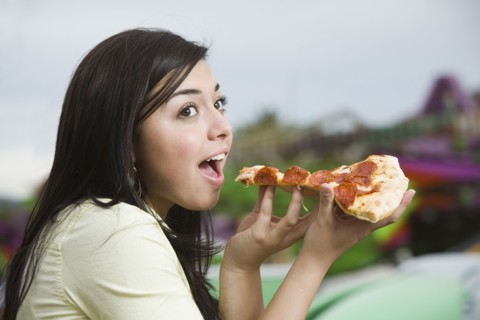 Mixed Race teenaged girl eating pizza