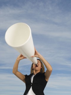 Hispanic businesswoman yelling into megaphone