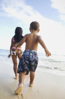 Pacific Islander siblings running on beach