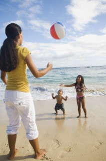 Pacific Islander mother and children playing with beach ball