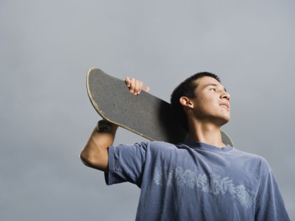 Mixed race teenager standing with skateboard
