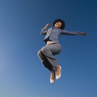 African businesswoman jumping in mid-air