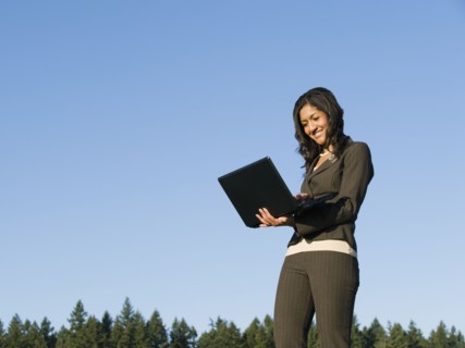 Mixed race businesswoman using laptop outdoors