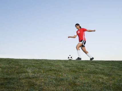 Mixed race woman kicking soccer ball