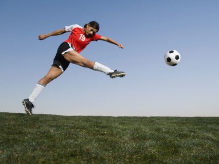 Mixed race woman kicking soccer ball