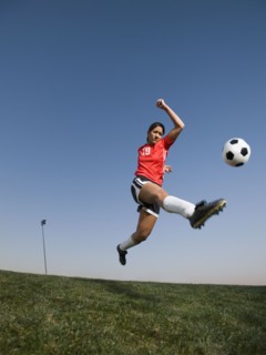 Mixed race woman kicking soccer ball