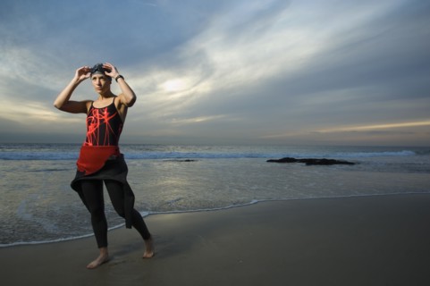 Hispanic woman in wetsuit on beach