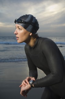Hispanic woman in wetsuit on beach
