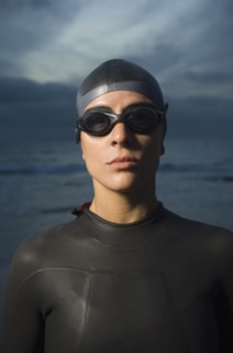Hispanic woman in wetsuit on beach