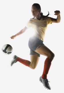 Mixed race soccer player kicking soccer ball in mid-air