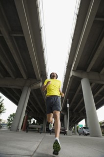 Mixed race man running under freeway overpass