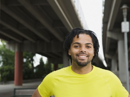 Mixed race man smiling under freeway overpass