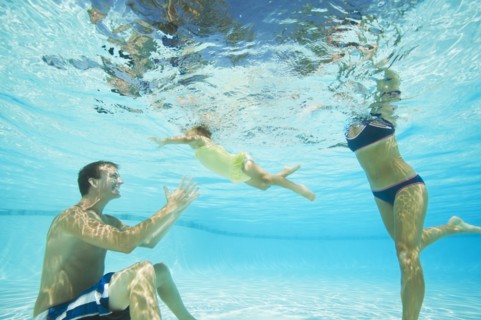 Parents swimming in swimming pool with daughter