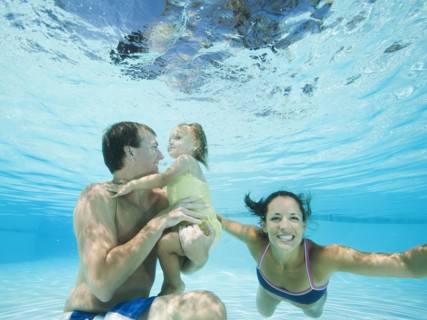 Parents swimming in swimming pool with daughter
