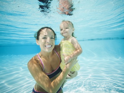 Mother underwater in swimming pool with daughter