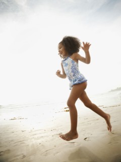 Mixed race girl in bathing suit running on beach