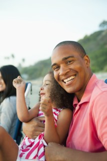 Smiling father holding daughter on beach