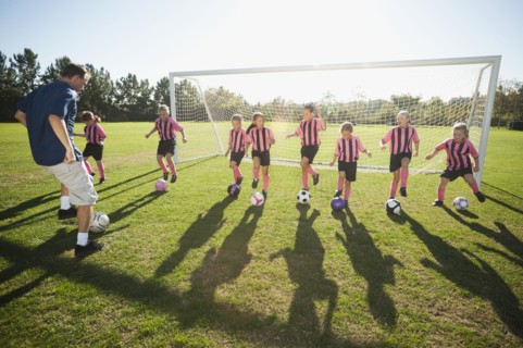 Coach practicing with girl soccer players