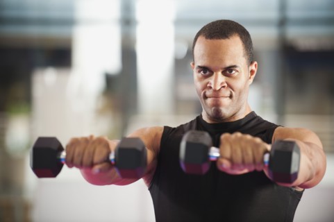 Mixed race man exercising with hand weights in health club