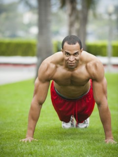 Mixed race man doing push-ups in park