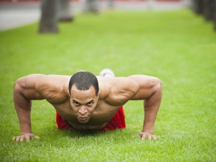 Mixed race man doing push-ups in park