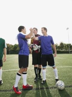 Soccer players cheering on soccer field