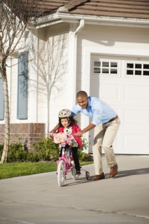 Father helping daughter learn to ride a bike