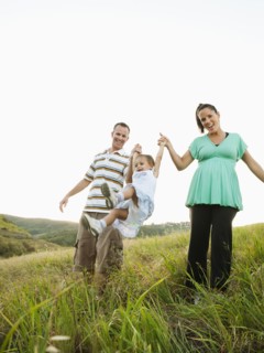 Happy parents swinging daughter in field