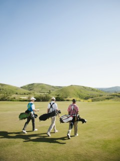 Men carrying golf bags on golf course