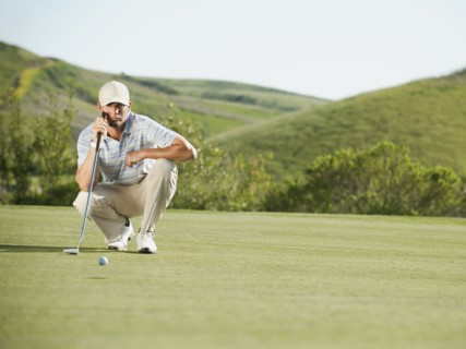 Caucasian golfer checking the ground on golf course