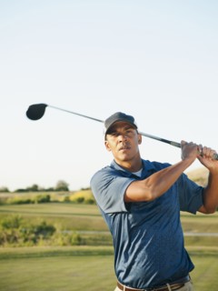 Black golfer swinging golf club