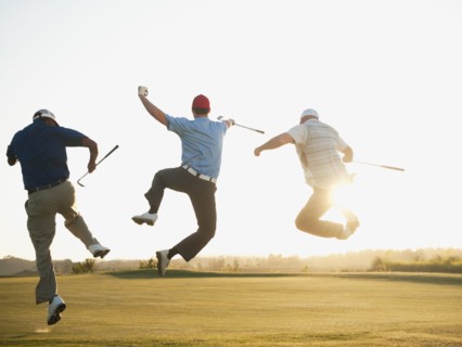 Excited golfers jumping in mid-air on golf course