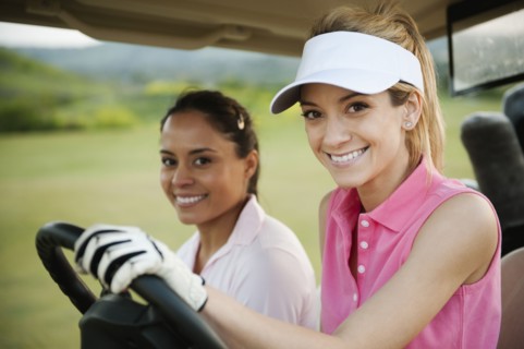 Women driving golf cart on golf course