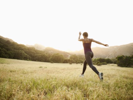 Mixed race woman running through remote field